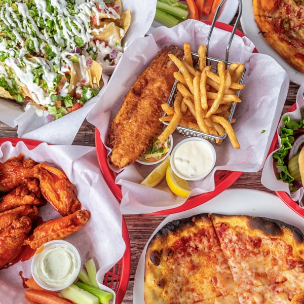 Overhead view of nachos, fish and chips, chicken wings, and a cheese pizza from The 377 Brewery.