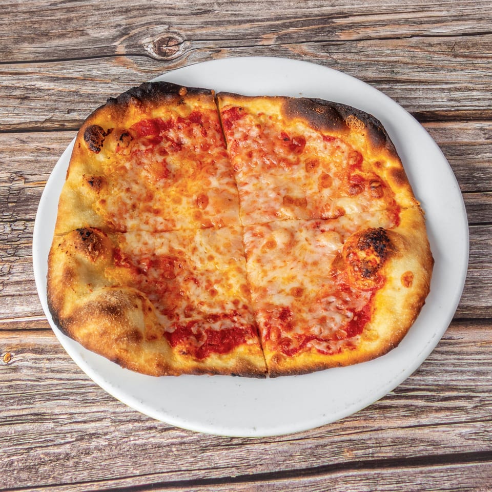A freshly baked, cheesy pizza with a crispy crust, sliced into four pieces on a white plate.