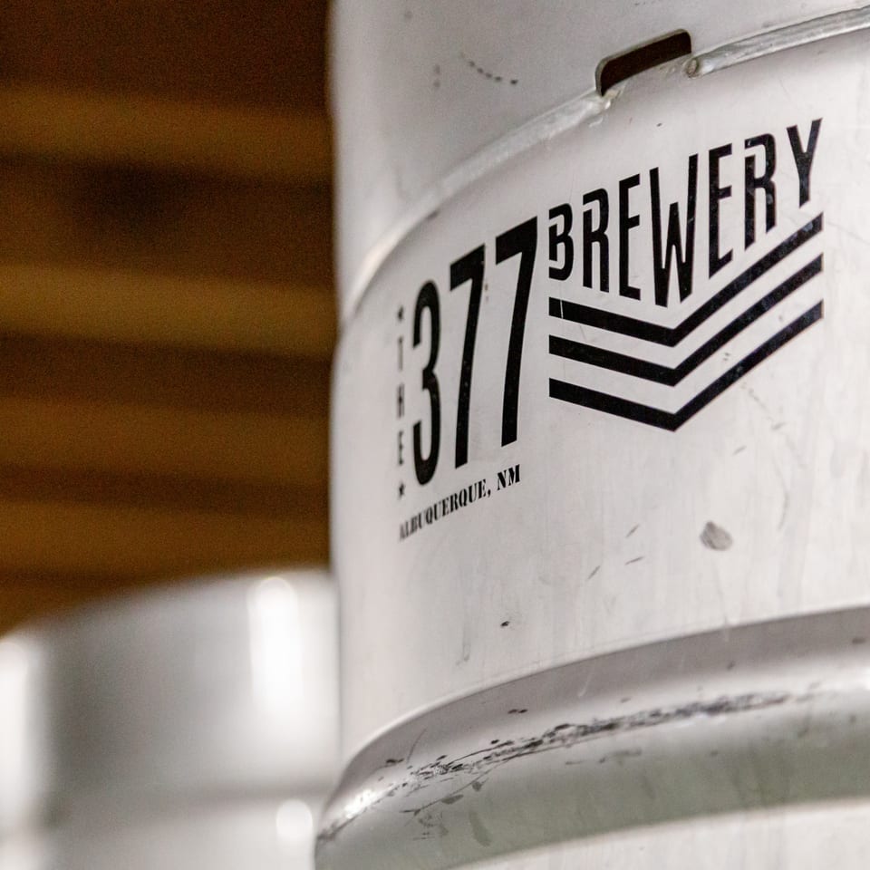 Close-up of a silver beer keg with "The 377 Brewery Albuquerque, NM" logo in black.