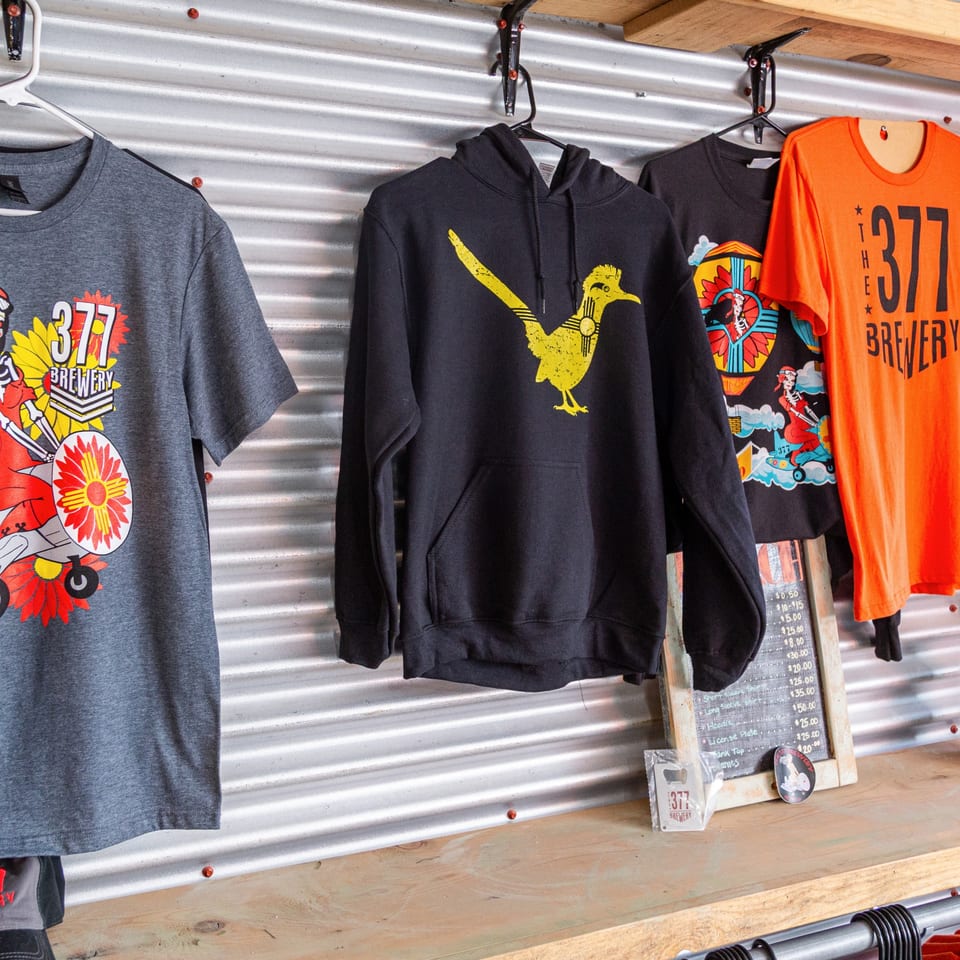 Merchandise from The 377 Brewery, including t-shirts, a hoodie, and a price list.